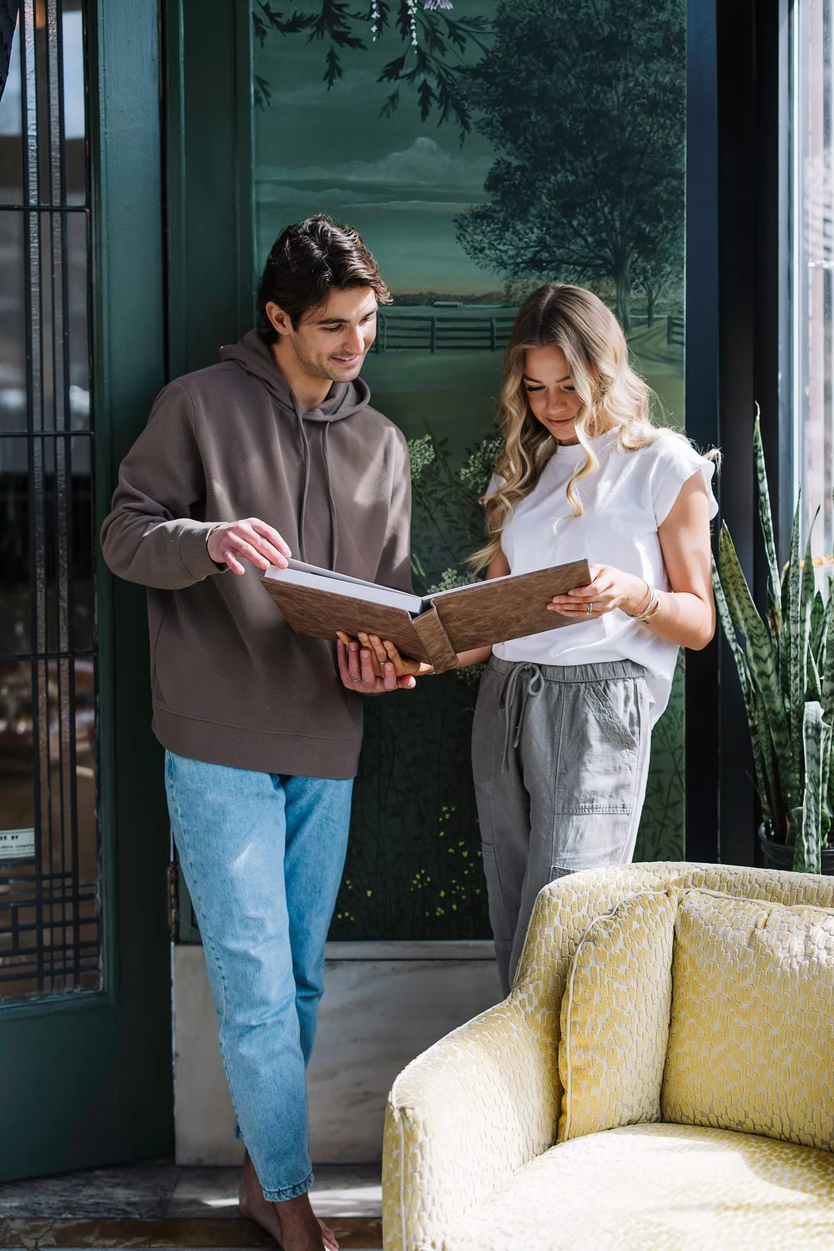 A couple standing together by a window, looking through a printed album