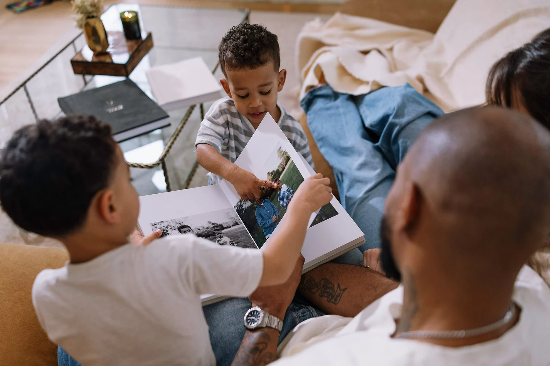 Parents and their children gathered around an album, with a child pointing at a photograph