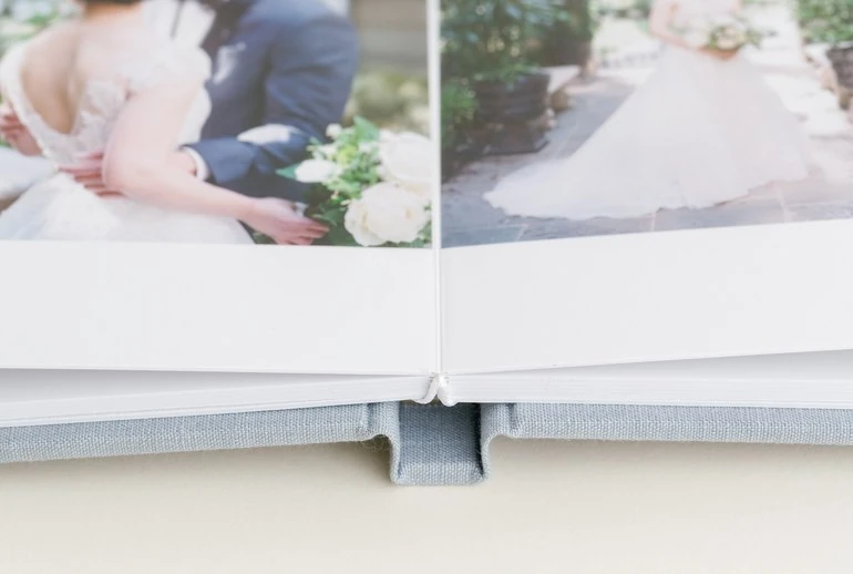 Close view of thick layflat album pages displaying wedding portraits and floral details