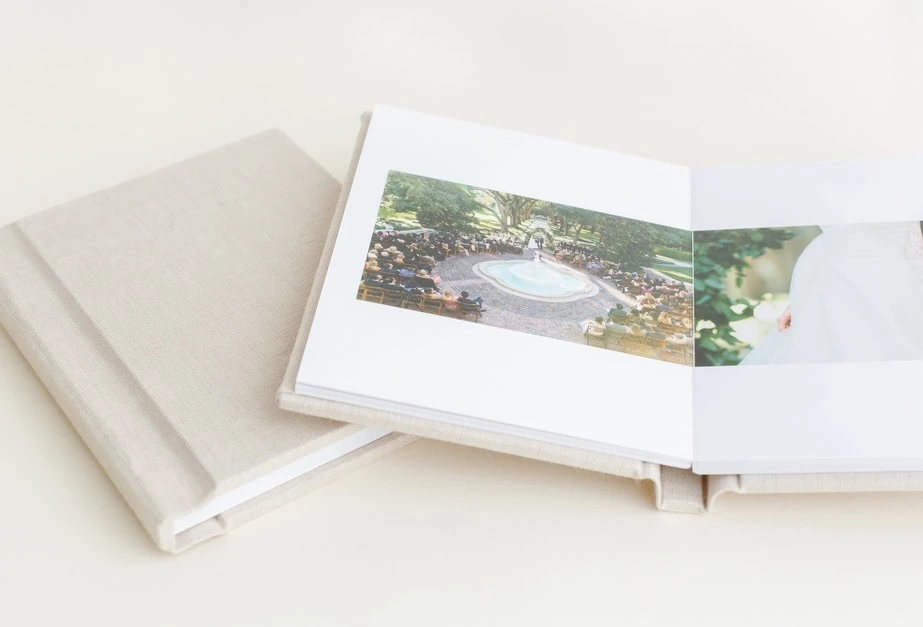 An open wedding album and its ivory cover, with a wedding portrait across the pages