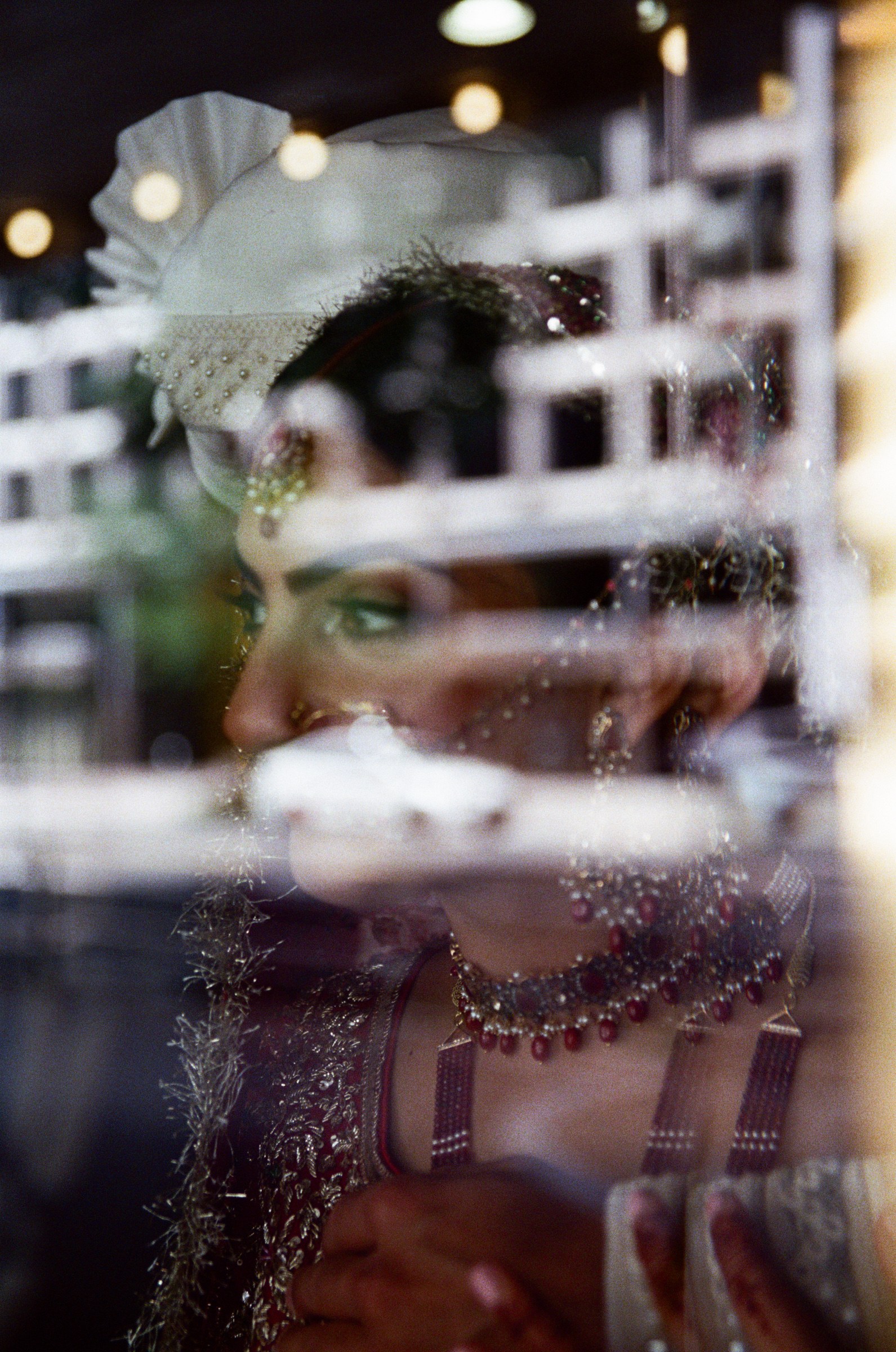 A bride seen through layered window reflections, photographed on film
